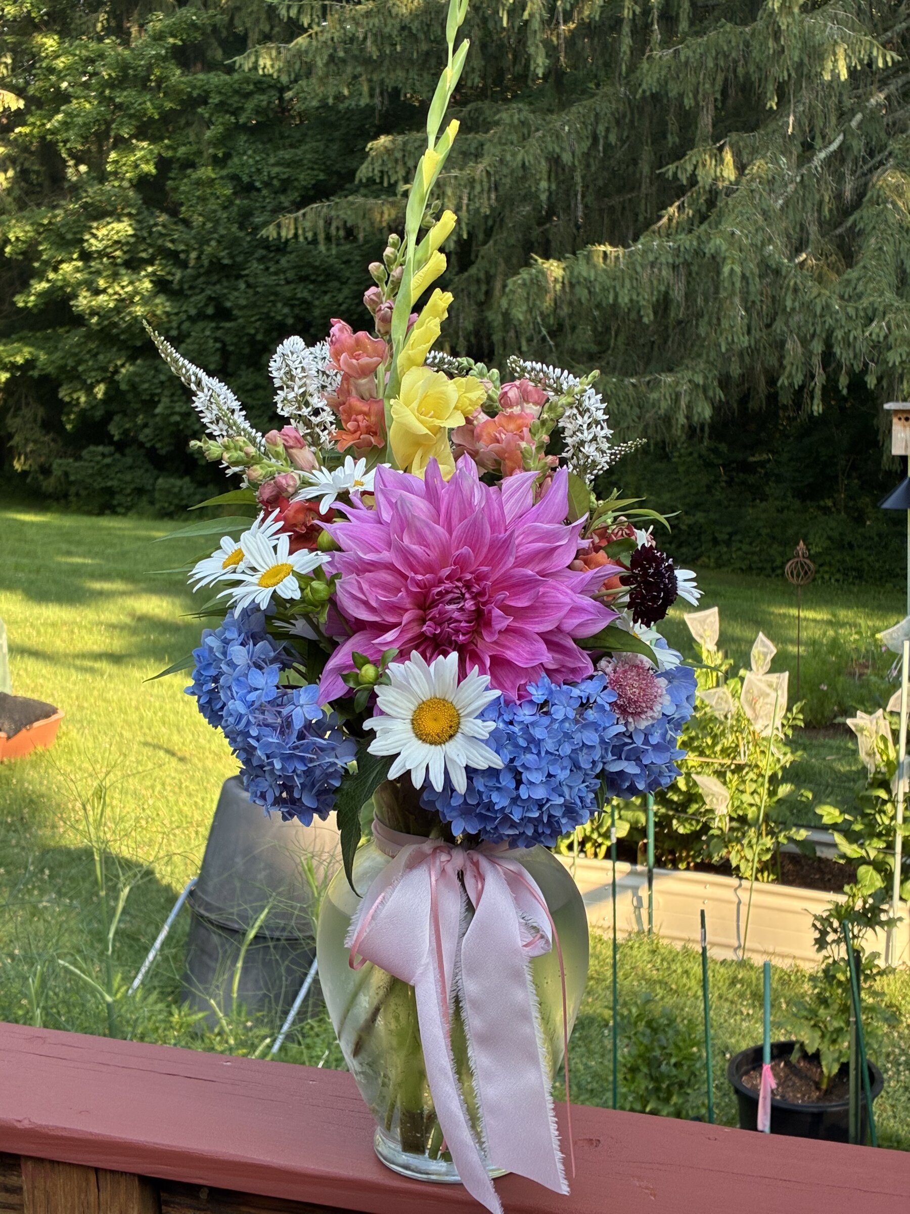 Colorful farm-grown bouquet in a glass vase outdoors.